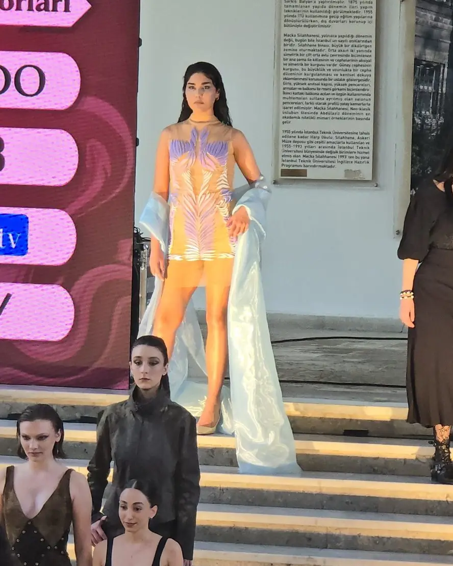 UTMÖK defilesinde lila ve beyaz TPU 95A yaprak motifli tül elbiseyle podyumda yürüyen model